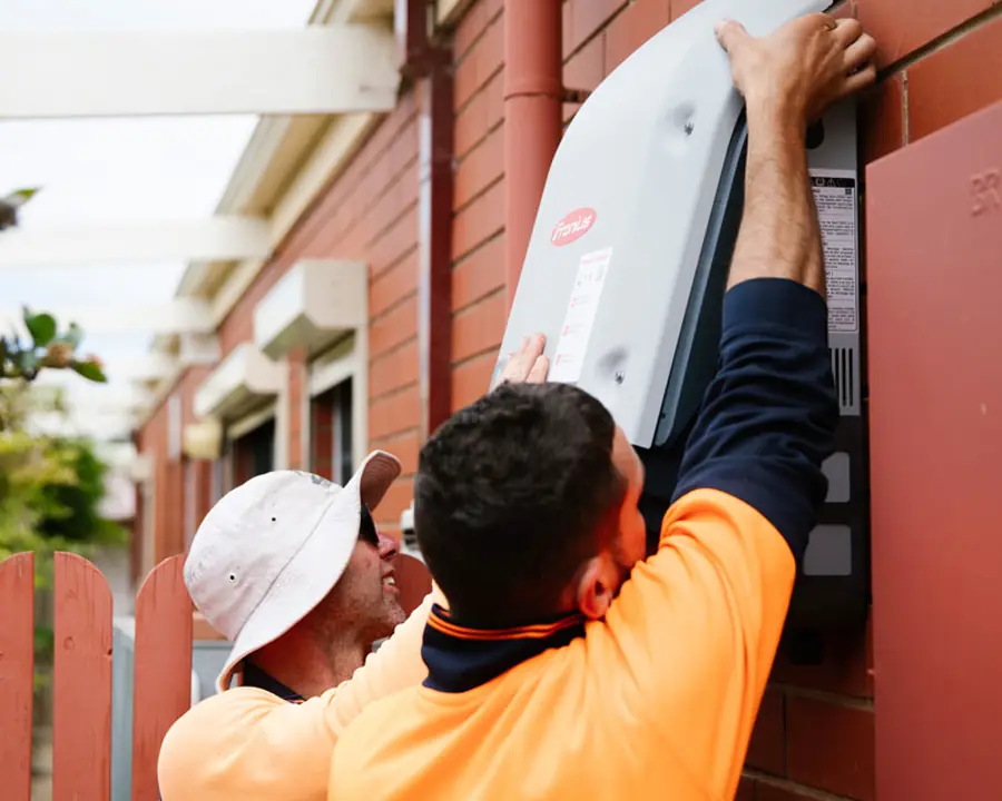 Solar technicians installing a wall-mounted inverter
