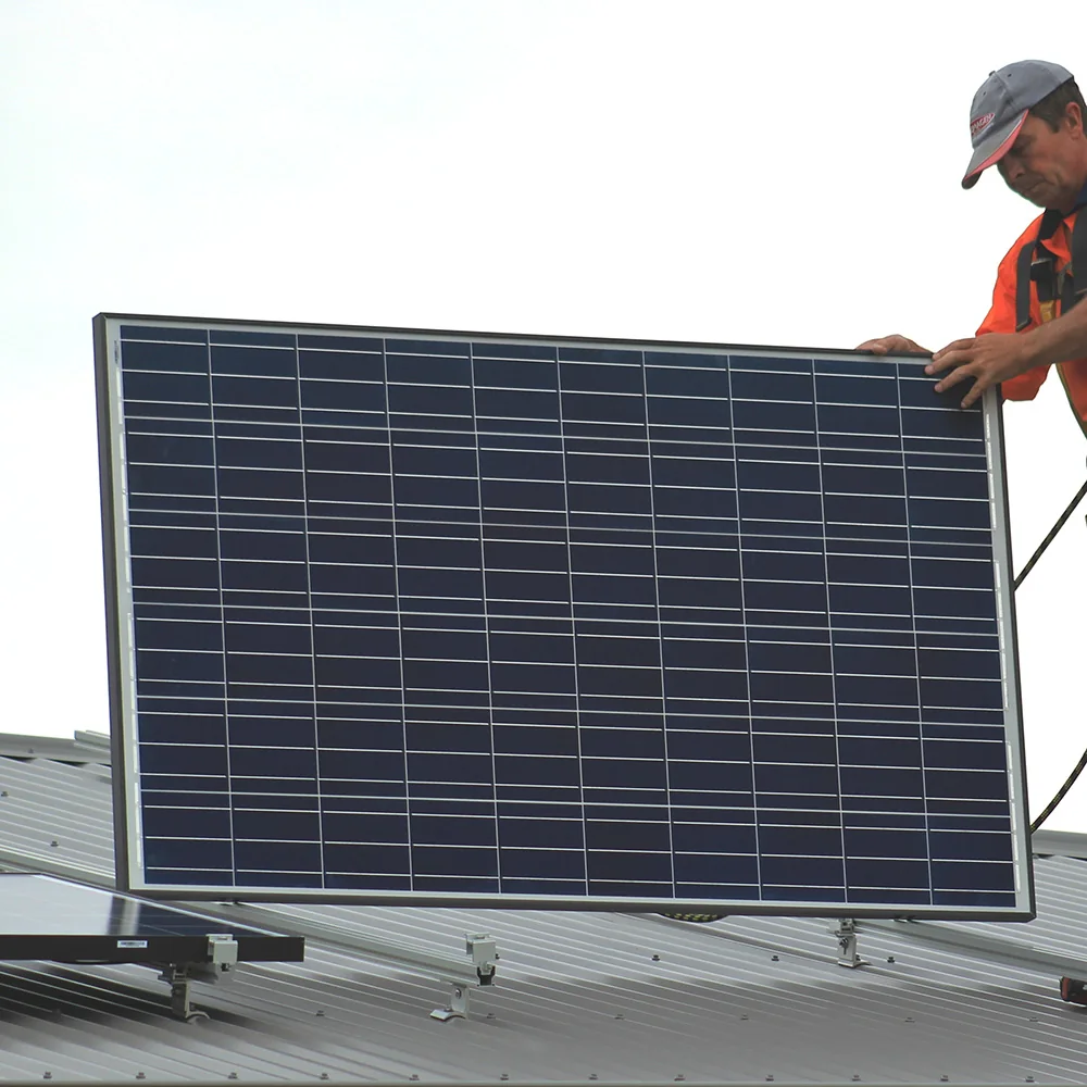 Solar installer positioning a photovoltaic panel on a commercial roof