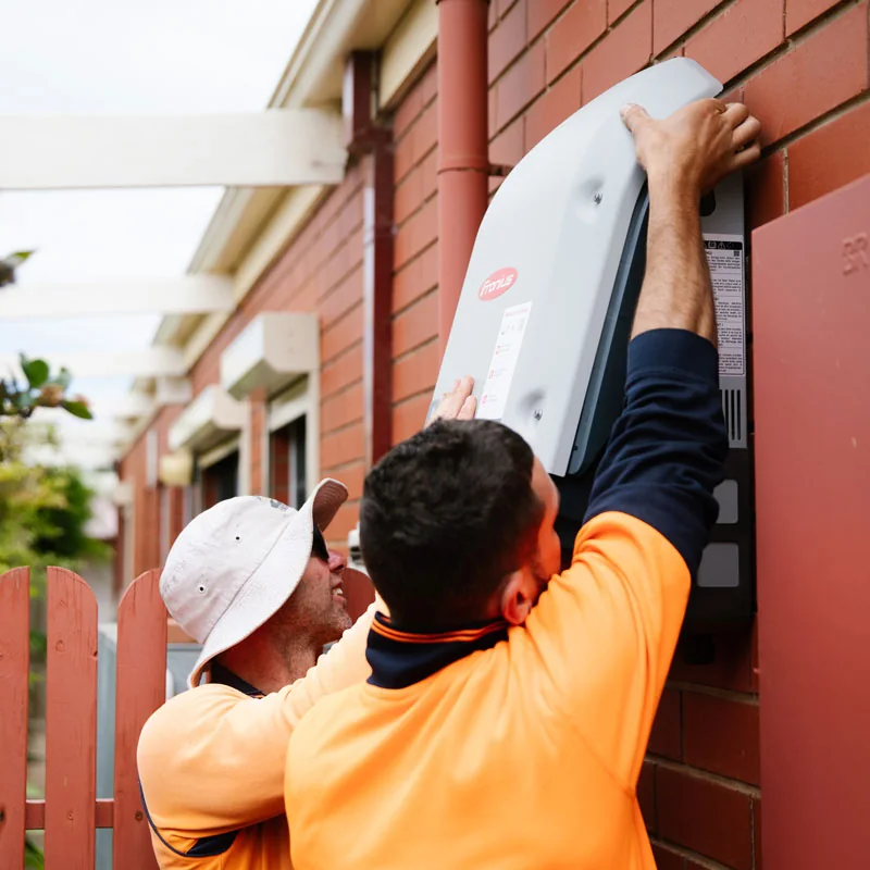 Solar technicians installing a wall-mounted inverter