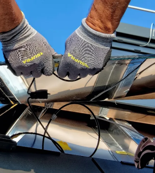 Solar technician repairing panel wiring on a rooftop